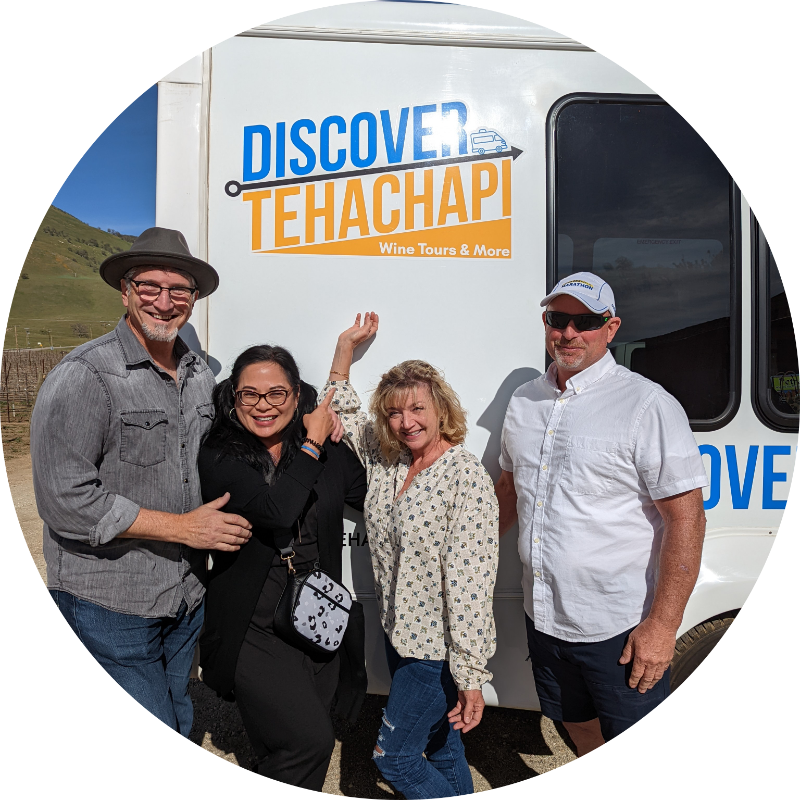 Renee and friends pointing at the Discover Tehachapi logo on the bus.